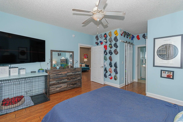 bedroom featuring ceiling fan, hardwood / wood-style floors, and a textured ceiling