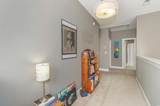 hallway featuring light colored carpet and a textured ceiling