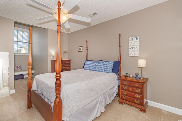 bedroom with a textured ceiling, light colored carpet, and ceiling fan