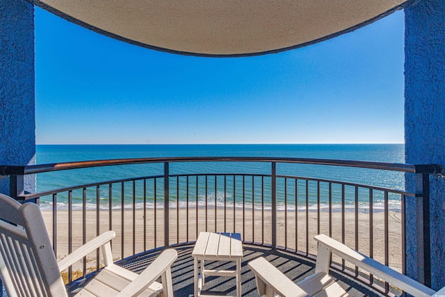 balcony with a water view and a view of the beach