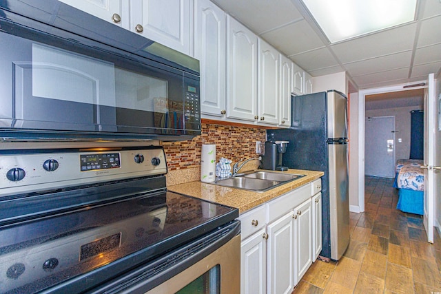 kitchen with white cabinetry, sink, light hardwood / wood-style floors, a paneled ceiling, and appliances with stainless steel finishes