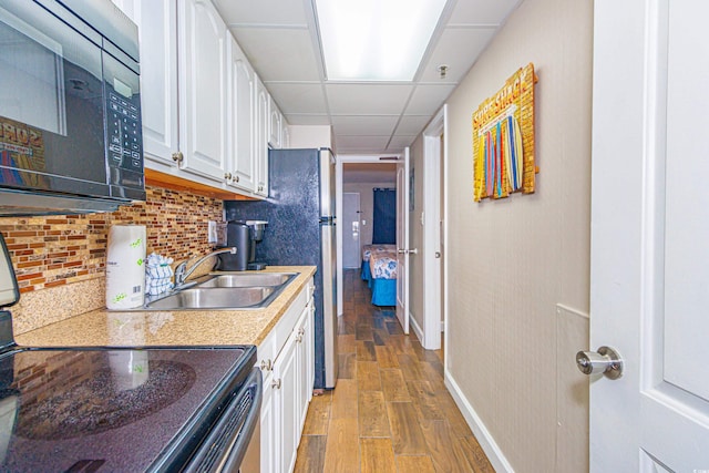 kitchen with white cabinetry, a drop ceiling, sink, light hardwood / wood-style flooring, and electric stove