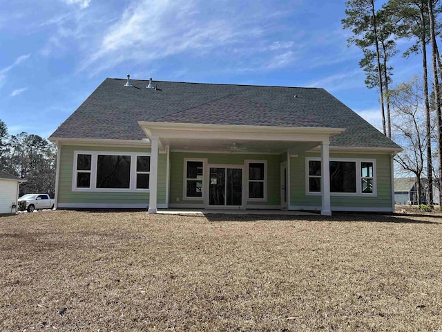 back of house featuring a patio area, a lawn, and roof with shingles