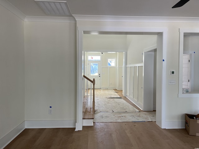 hallway featuring ornamental molding, wood finished floors, visible vents, and baseboards