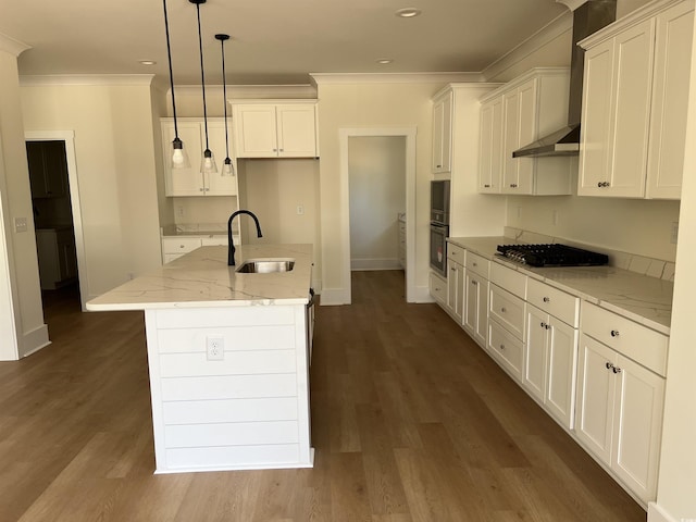 kitchen featuring an island with sink, light stone countertops, stainless steel gas stovetop, pendant lighting, and a sink