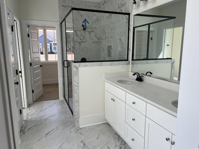 bathroom featuring marble finish floor, double vanity, a stall shower, a sink, and baseboards