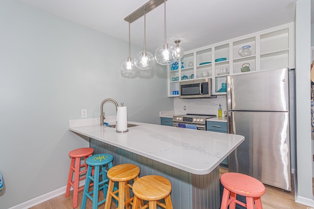 kitchen with kitchen peninsula, appliances with stainless steel finishes, sink, hanging light fixtures, and a breakfast bar area