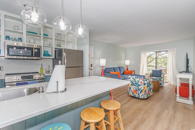 kitchen featuring light stone countertops, sink, light hardwood / wood-style flooring, a kitchen bar, and appliances with stainless steel finishes