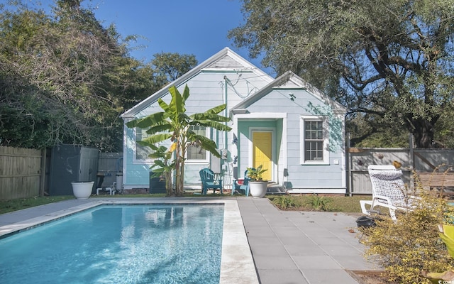 rear view of property featuring an outbuilding, a fenced in pool, and a patio area