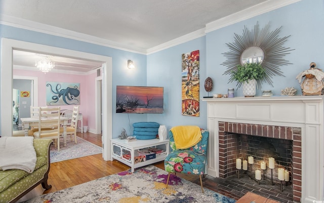 living room with crown molding, hardwood / wood-style floors, a chandelier, and a brick fireplace