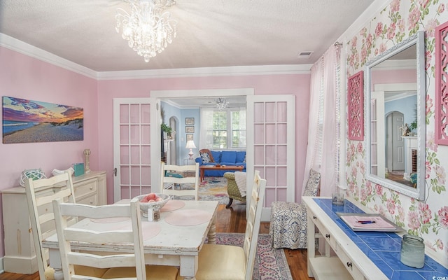 dining room with french doors, hardwood / wood-style flooring, ornamental molding, a textured ceiling, and a notable chandelier