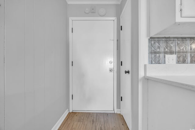 doorway featuring crown molding and light hardwood / wood-style floors