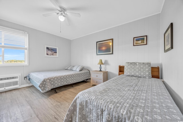 bedroom featuring a wall unit AC, ceiling fan, hardwood / wood-style floors, and ornamental molding