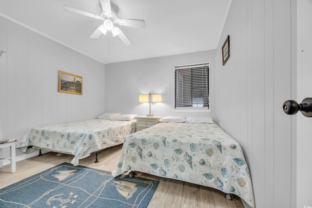 bedroom featuring hardwood / wood-style floors, ceiling fan, and wooden walls