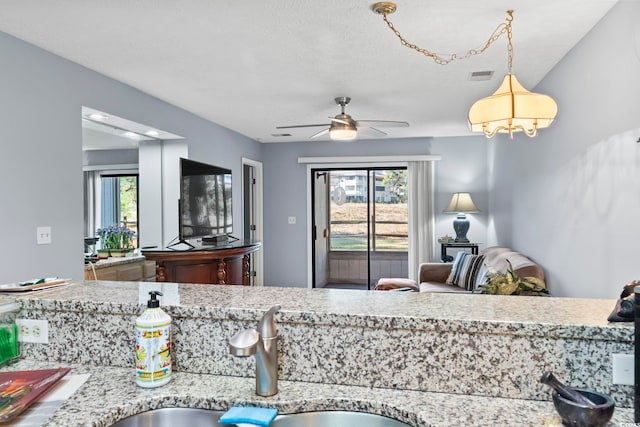 kitchen featuring ceiling fan, sink, and hanging light fixtures