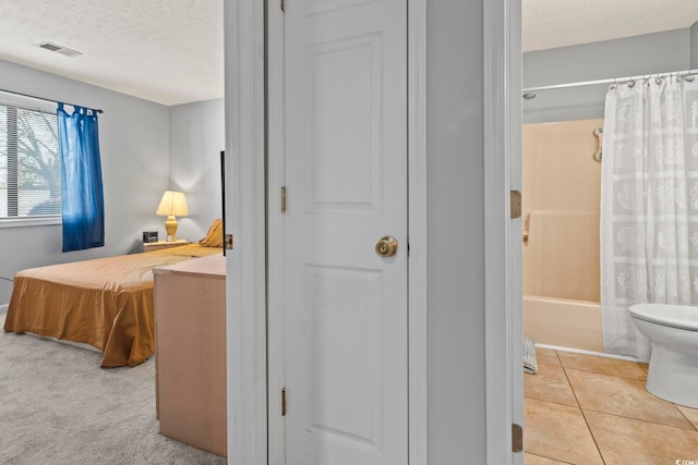 interior space featuring tile patterned flooring, shower / bath combo, a textured ceiling, and toilet