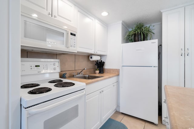 kitchen with white appliances, sink, light tile patterned floors, tasteful backsplash, and white cabinetry