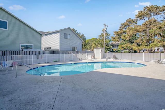 view of swimming pool featuring a patio and a shed