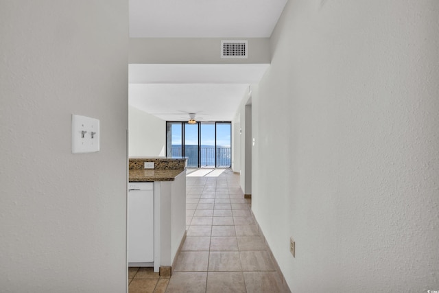 corridor with floor to ceiling windows and light tile patterned floors