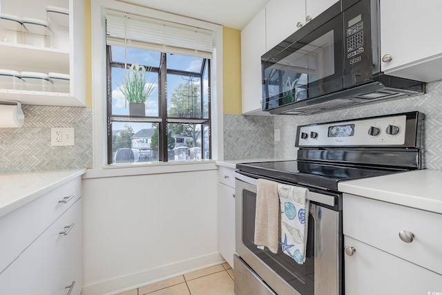 kitchen with electric stove, light tile patterned floors, white cabinetry, and decorative backsplash