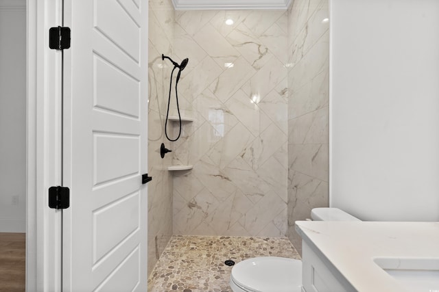 bathroom featuring a tile shower, vanity, and toilet