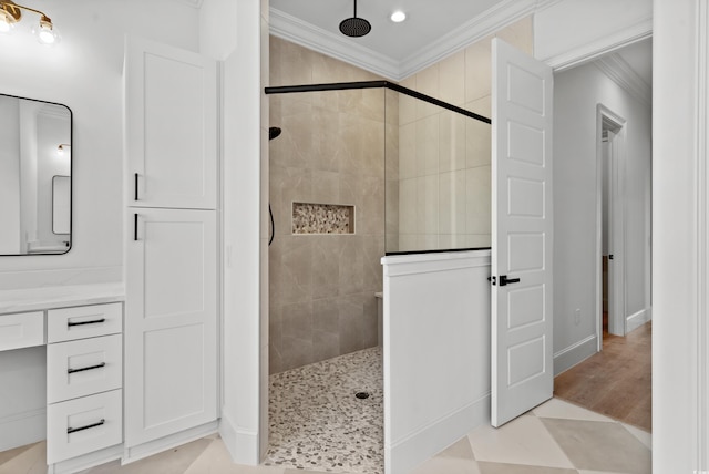 bathroom with a tile shower, vanity, and ornamental molding