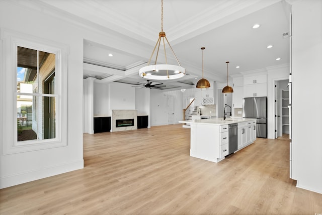 kitchen featuring appliances with stainless steel finishes, an island with sink, hanging light fixtures, and white cabinets