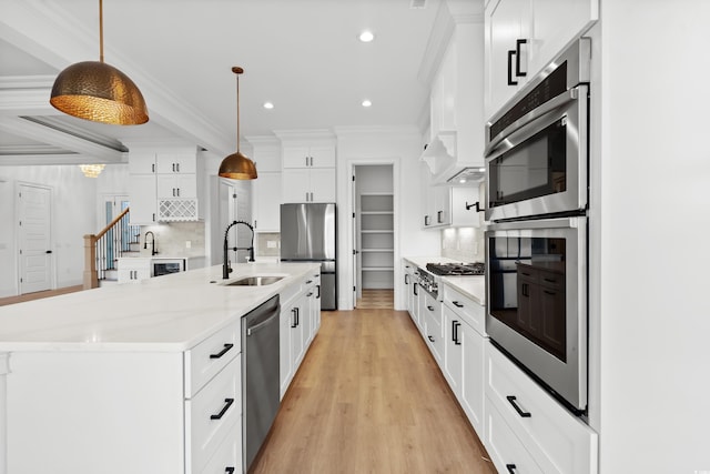 kitchen with an island with sink, decorative light fixtures, sink, and decorative backsplash