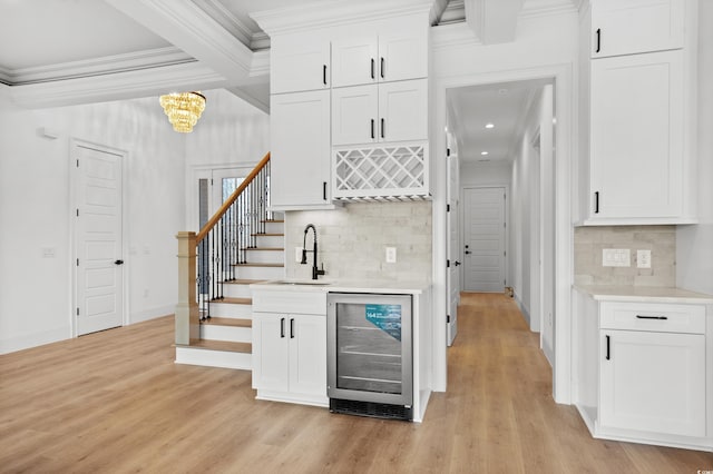 bar featuring crown molding, wine cooler, tasteful backsplash, white cabinets, and light wood-type flooring