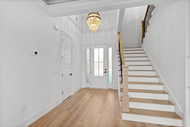 entrance foyer with an inviting chandelier, ornamental molding, and light hardwood / wood-style floors