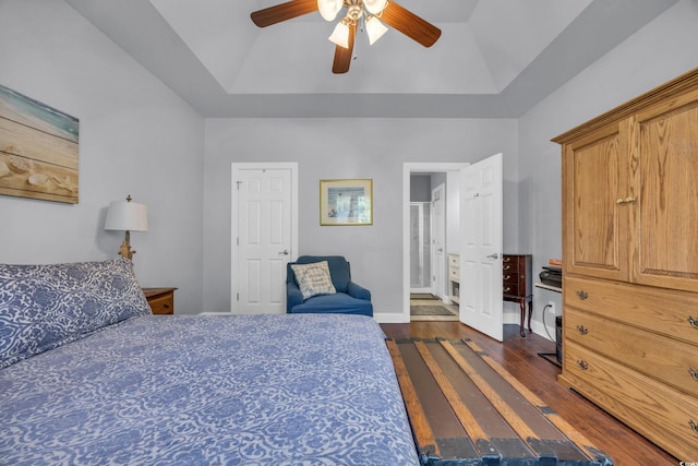 bedroom featuring lofted ceiling, a raised ceiling, ceiling fan, and dark wood-type flooring