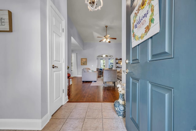 foyer with ceiling fan with notable chandelier and light wood-type flooring