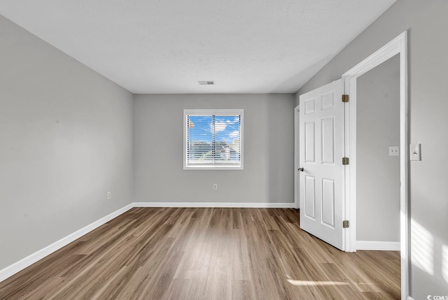 empty room featuring light wood-type flooring and a textured ceiling