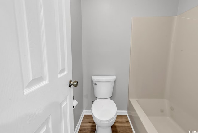 bathroom featuring hardwood / wood-style floors, a tub to relax in, and toilet