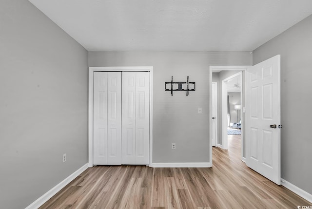 unfurnished bedroom with light wood-type flooring and a closet