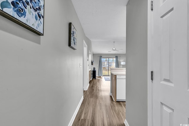 hall with a textured ceiling and light wood-type flooring