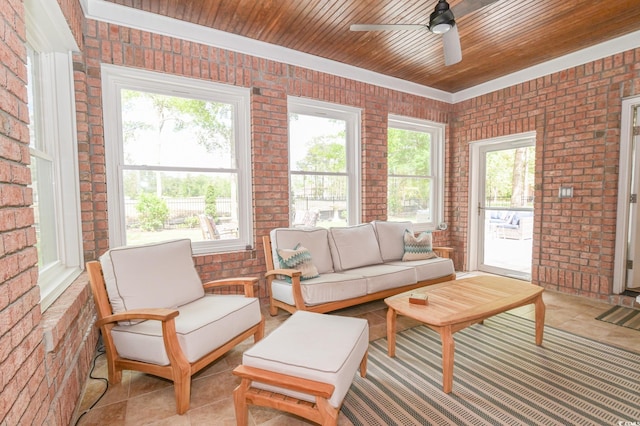 living room with a wealth of natural light, ceiling fan, and brick wall