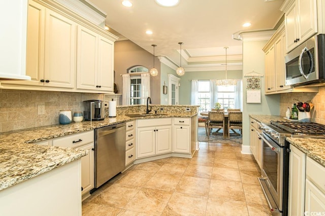 kitchen with backsplash, sink, decorative light fixtures, and appliances with stainless steel finishes