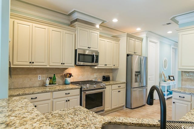 kitchen featuring light stone countertops, appliances with stainless steel finishes, tasteful backsplash, ornamental molding, and sink