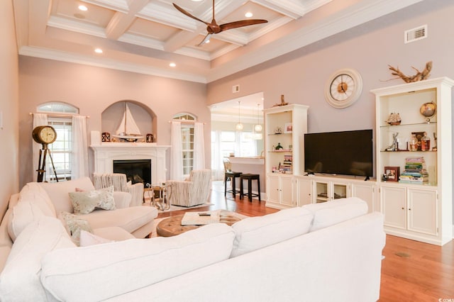 living room with ceiling fan, plenty of natural light, coffered ceiling, and light wood-type flooring