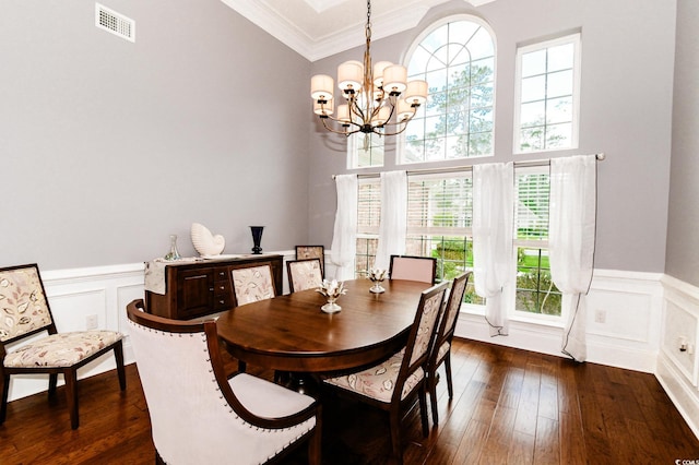 dining space with crown molding, dark hardwood / wood-style floors, and an inviting chandelier