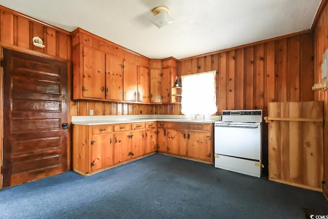 kitchen with white range with electric cooktop, sink, dark carpet, and wood walls