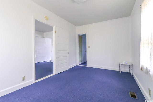 unfurnished bedroom with dark carpet