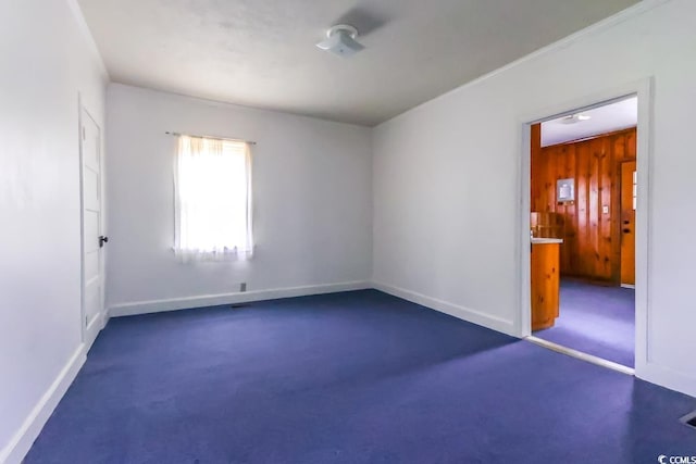 carpeted spare room featuring wooden walls