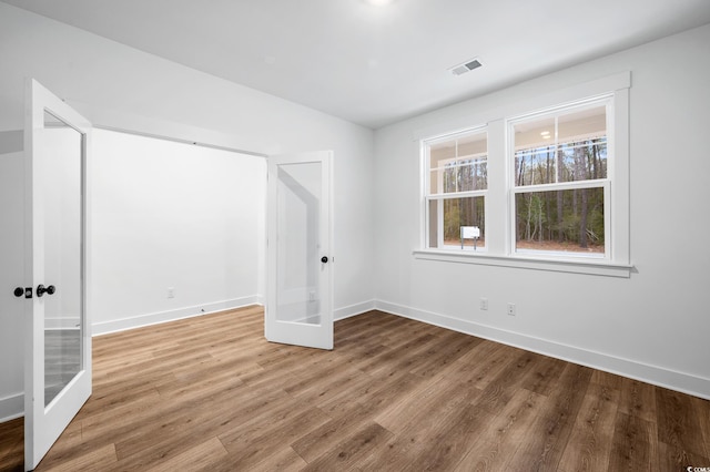 unfurnished room with hardwood / wood-style floors and french doors