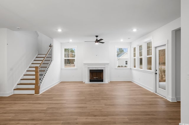 unfurnished living room with ceiling fan, plenty of natural light, a fireplace, and light hardwood / wood-style floors