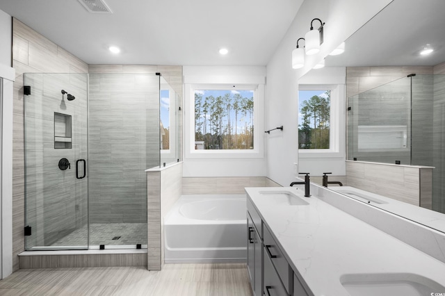 bathroom featuring shower with separate bathtub and vanity