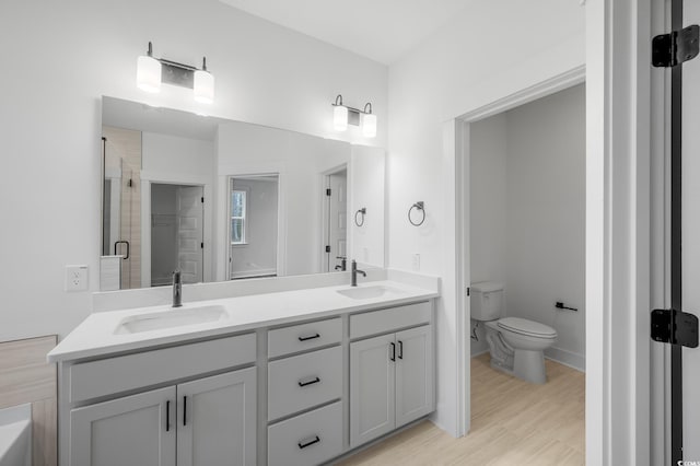 bathroom featuring vanity, hardwood / wood-style flooring, a shower with door, and toilet