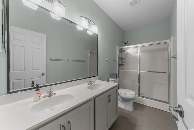 bathroom featuring vanity, toilet, and a shower with shower door