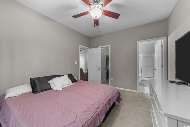 bedroom with ceiling fan, a walk in closet, light carpet, and connected bathroom